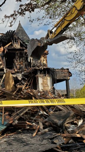 A fire-damaged house is demolished.